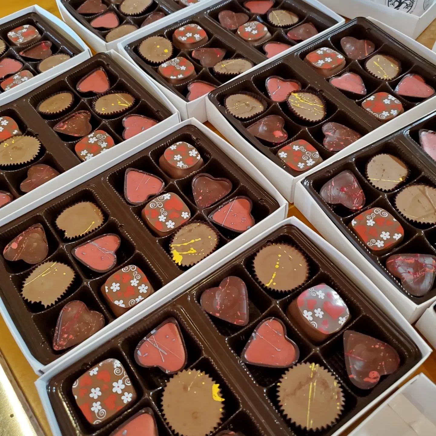 Assorted chocolate gift boxes with decorative shapes and colorful coatings.