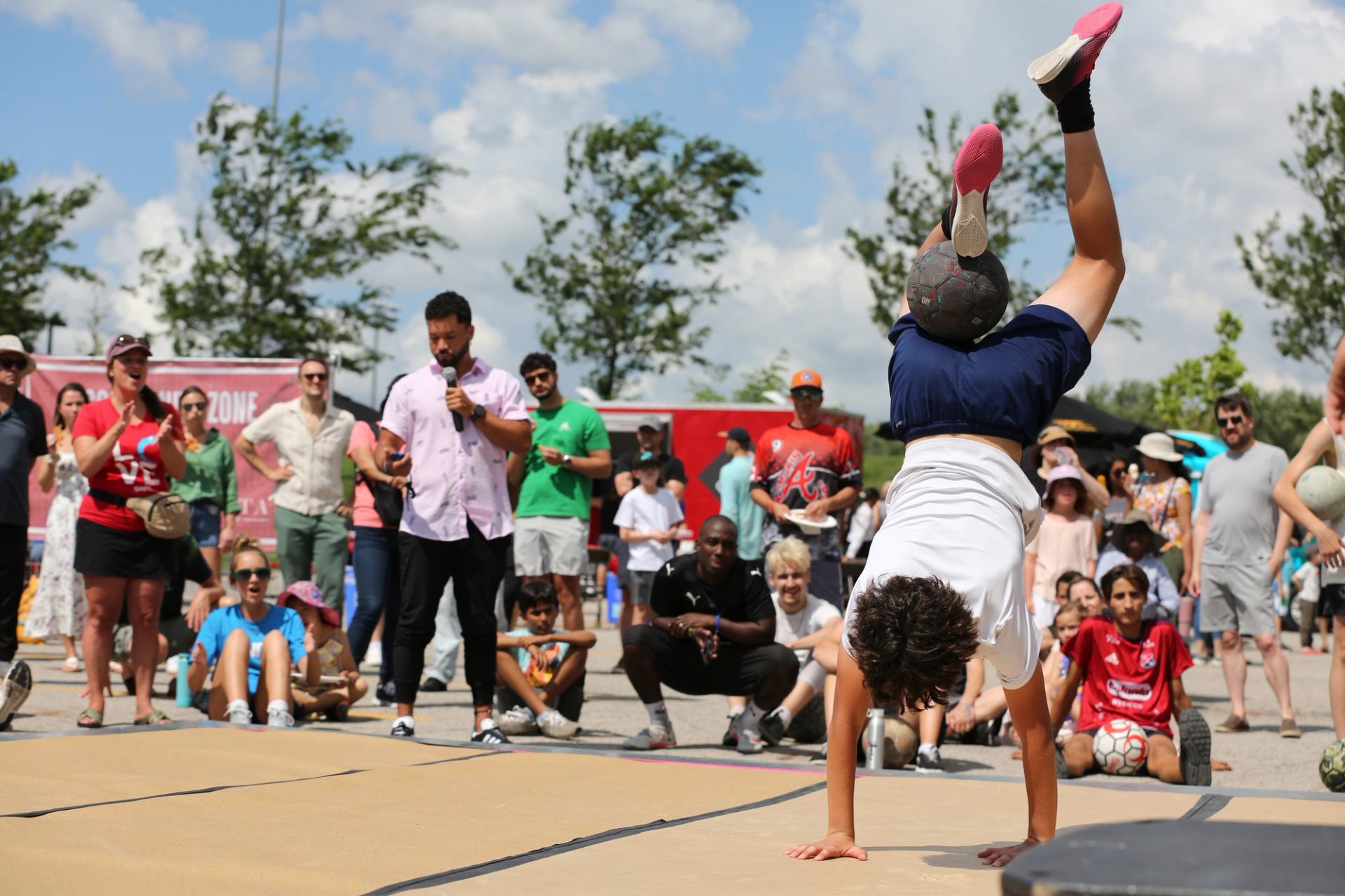 Performer does handstand outdoors as crowd watches at The Good Games.