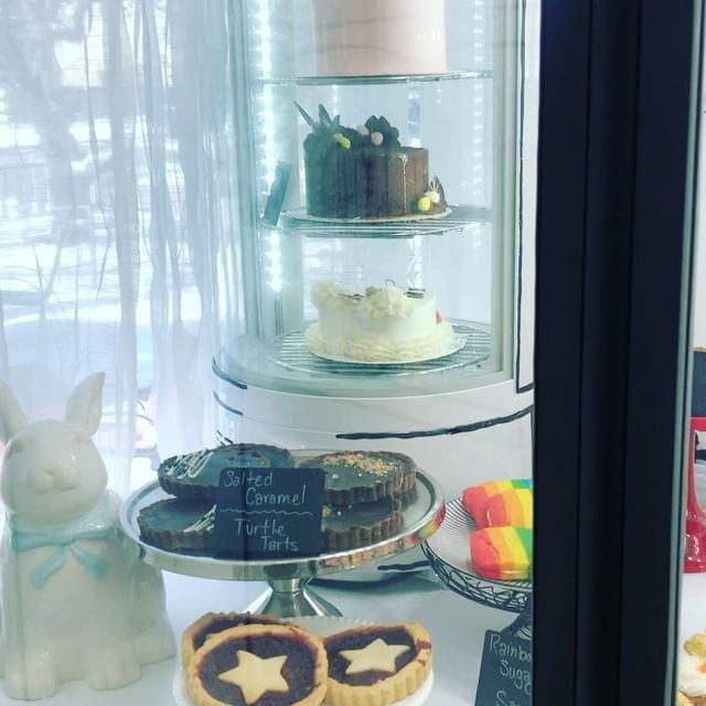 Bakery display case with cakes, tarts, and colorful rainbow treats.
