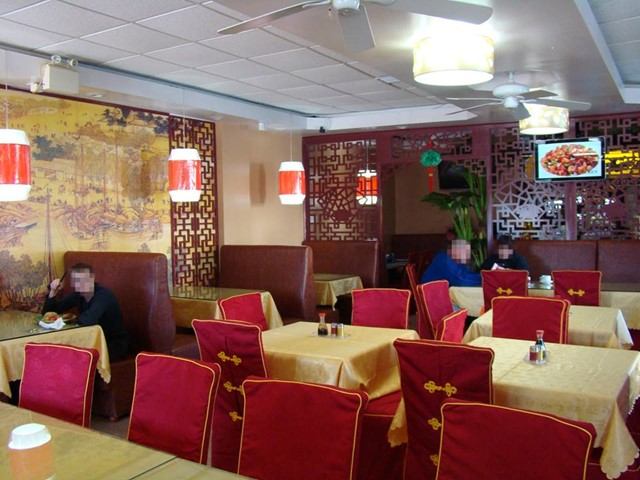 Restaurant dining area with red chairs, patterned walls, and a table set with condiments.