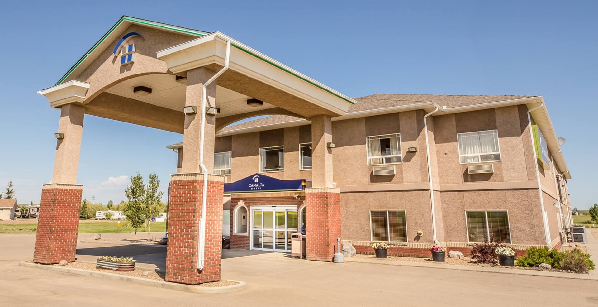 Canalta Hotel exterior with covered entrance, brick pillars and surrounding parking area.
