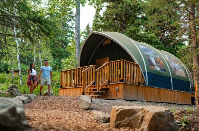 A couple goes for a walk down the pathway past the lodge at Glamping Resorts in Castle Provincial Park.