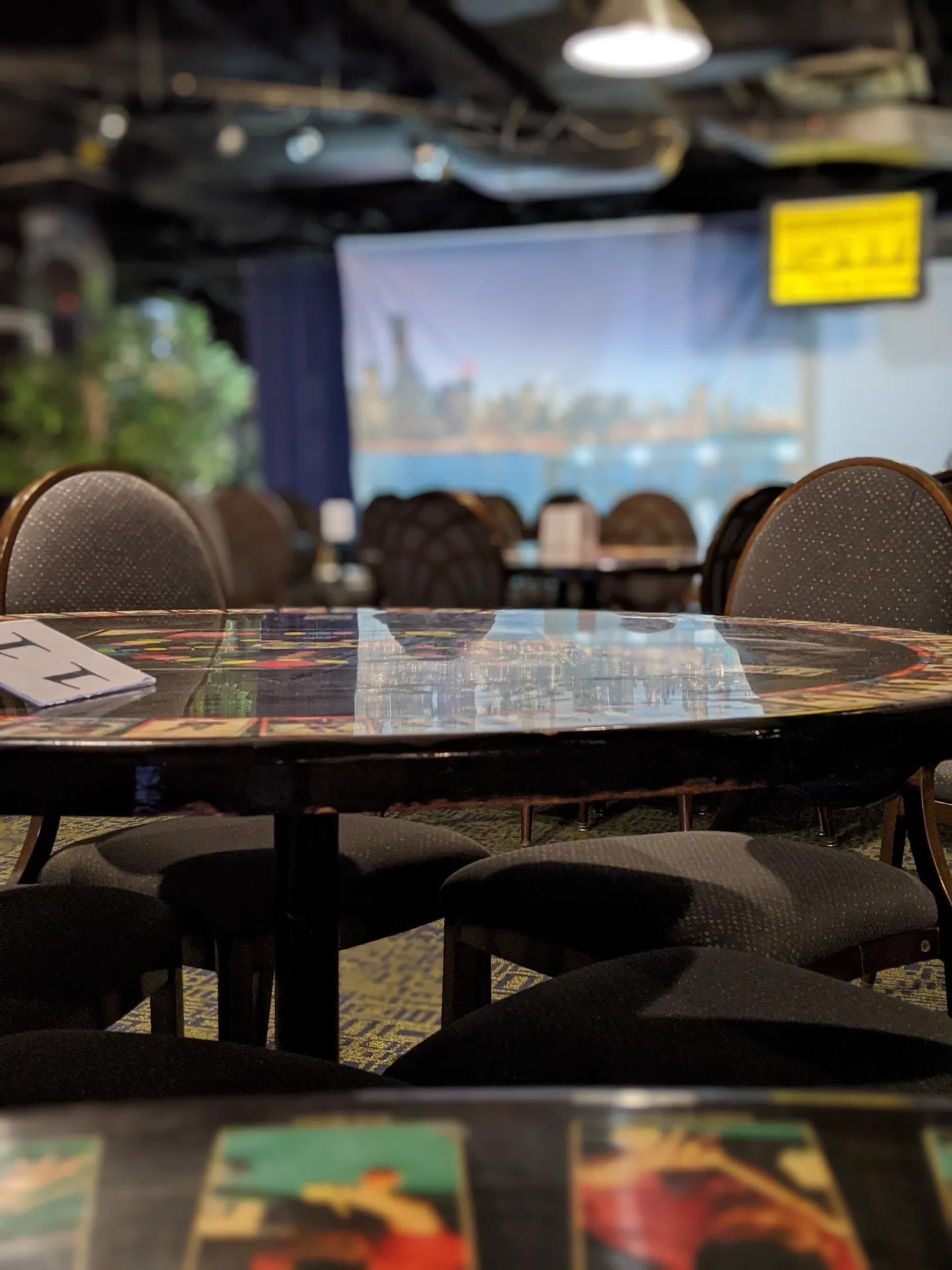 Round tables with patterned tops and chairs in a dim indoor event space.