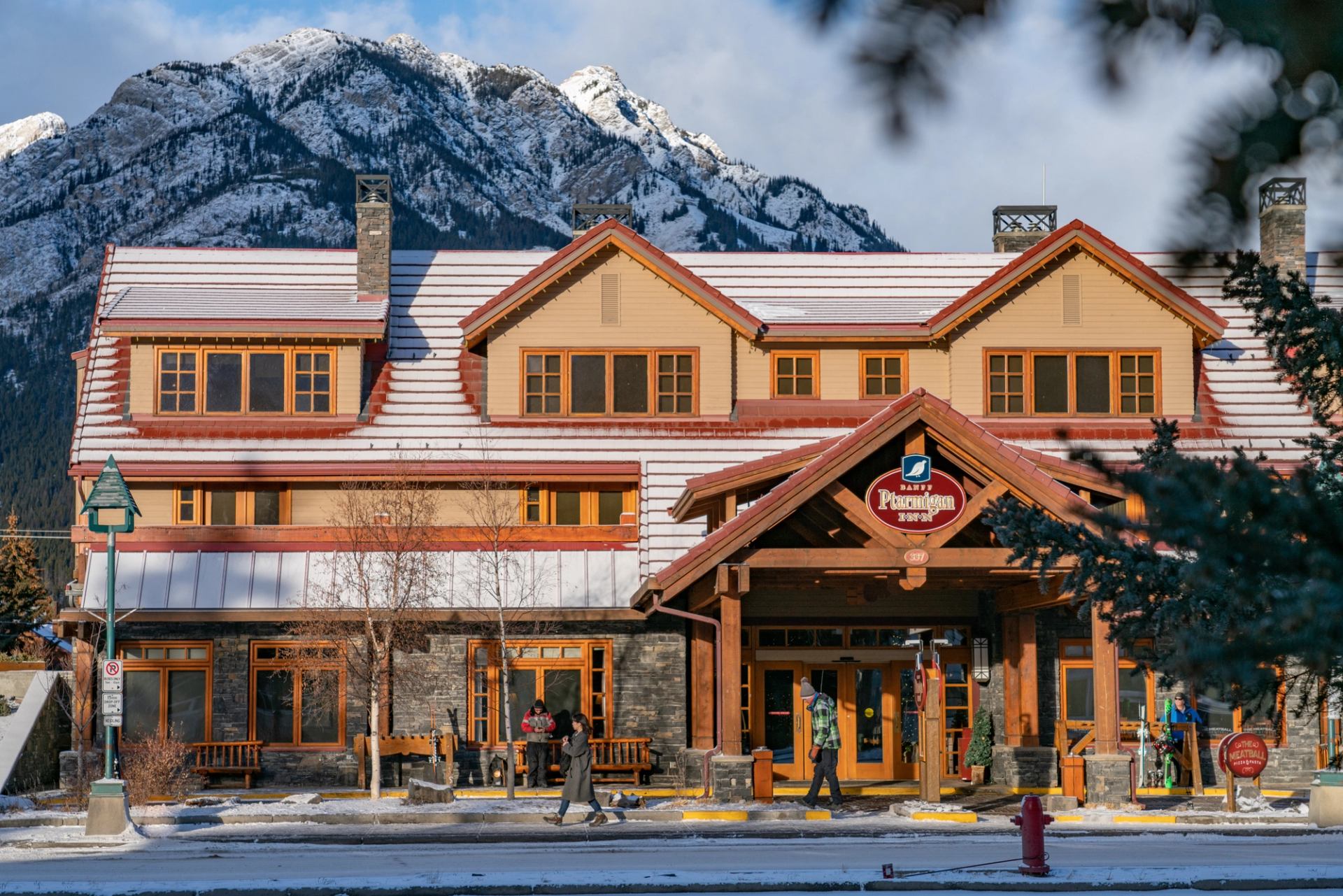 Banff Ptarmigan Inn with snowy roof and mountain backdrop.
