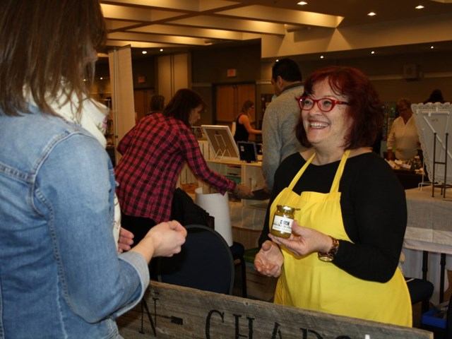 Guests sampling local products at an indoor event with a vendor table and displays.