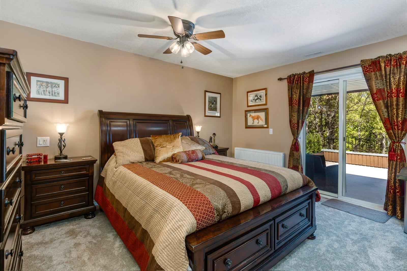 Bedroom with striped quilt, dark wood furniture and sliding doors to patio.