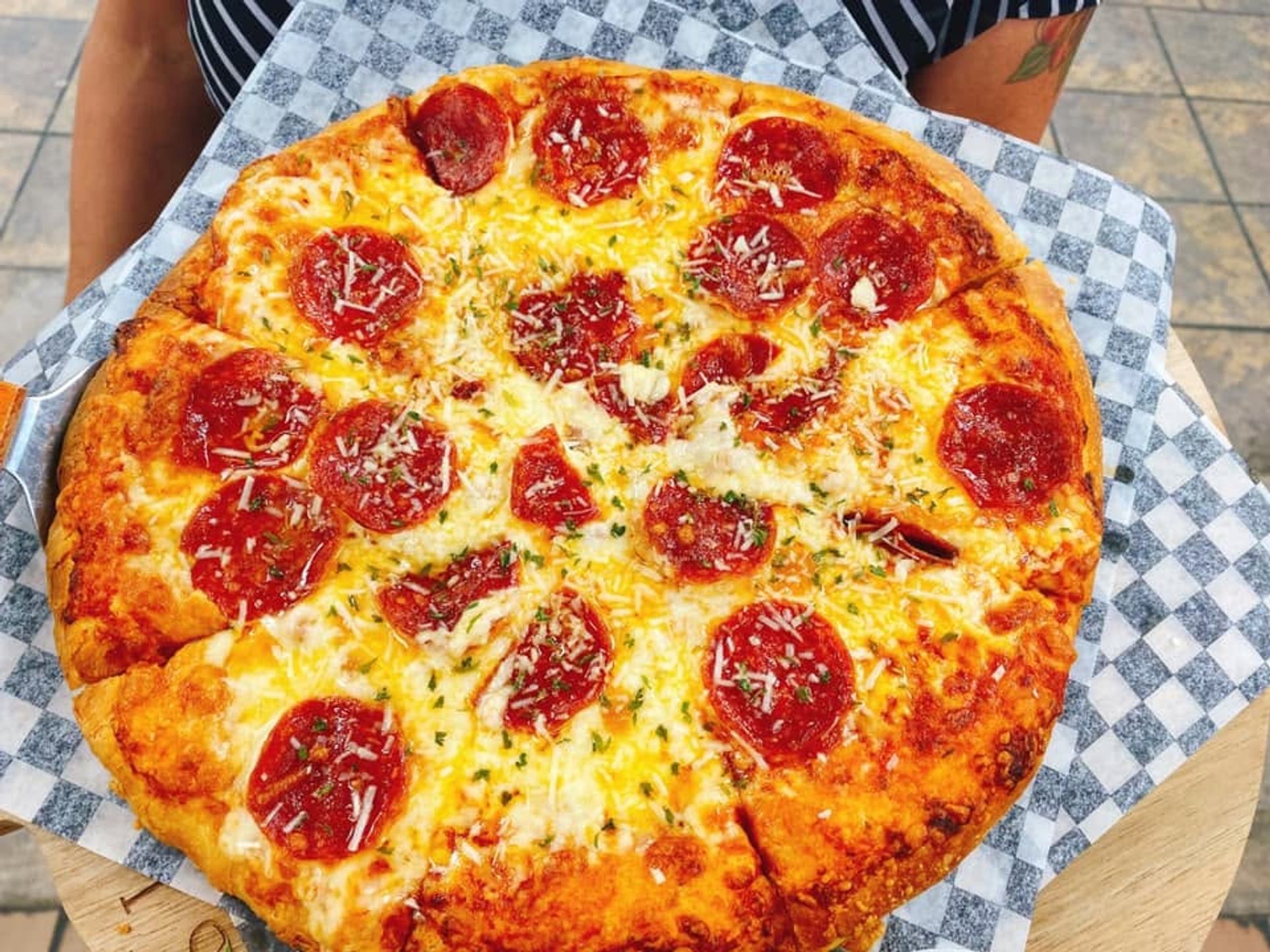 A freshly baked pepperoni pizza topped with melted cheese and herbs is served on a tray.