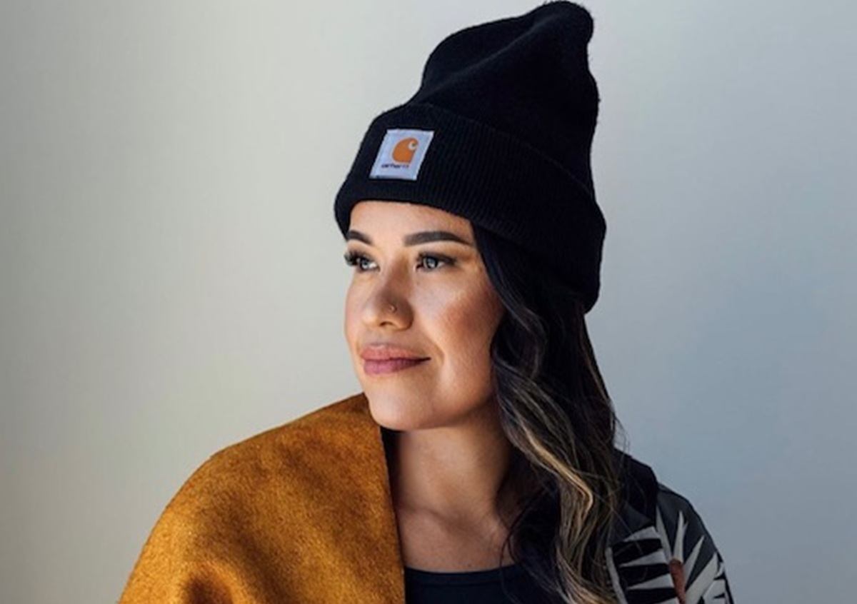 Person wearing a black Carhartt toque and mustard shawl against plain background.