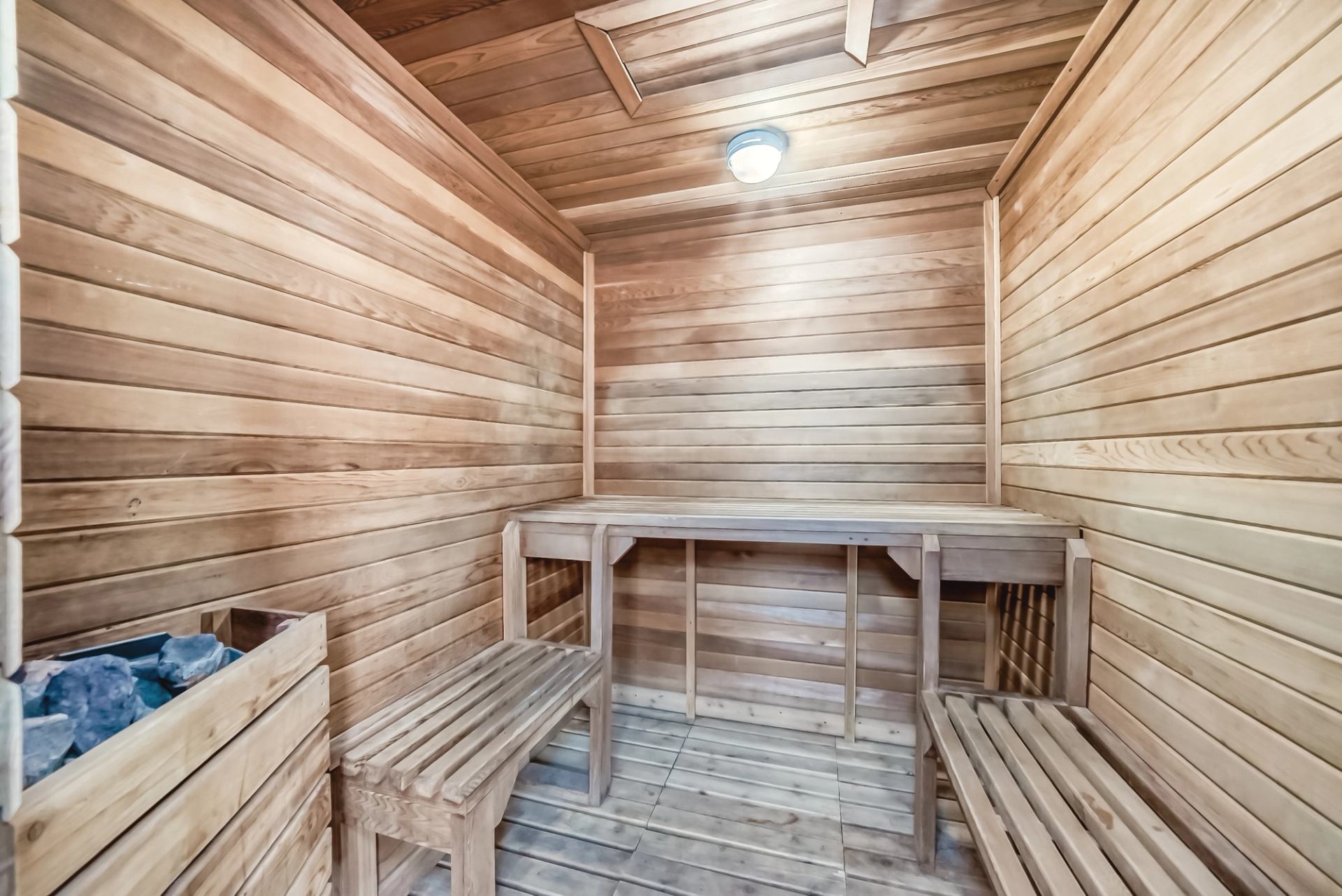 Wood-paneled sauna room with benches and a heater for a relaxing experience.