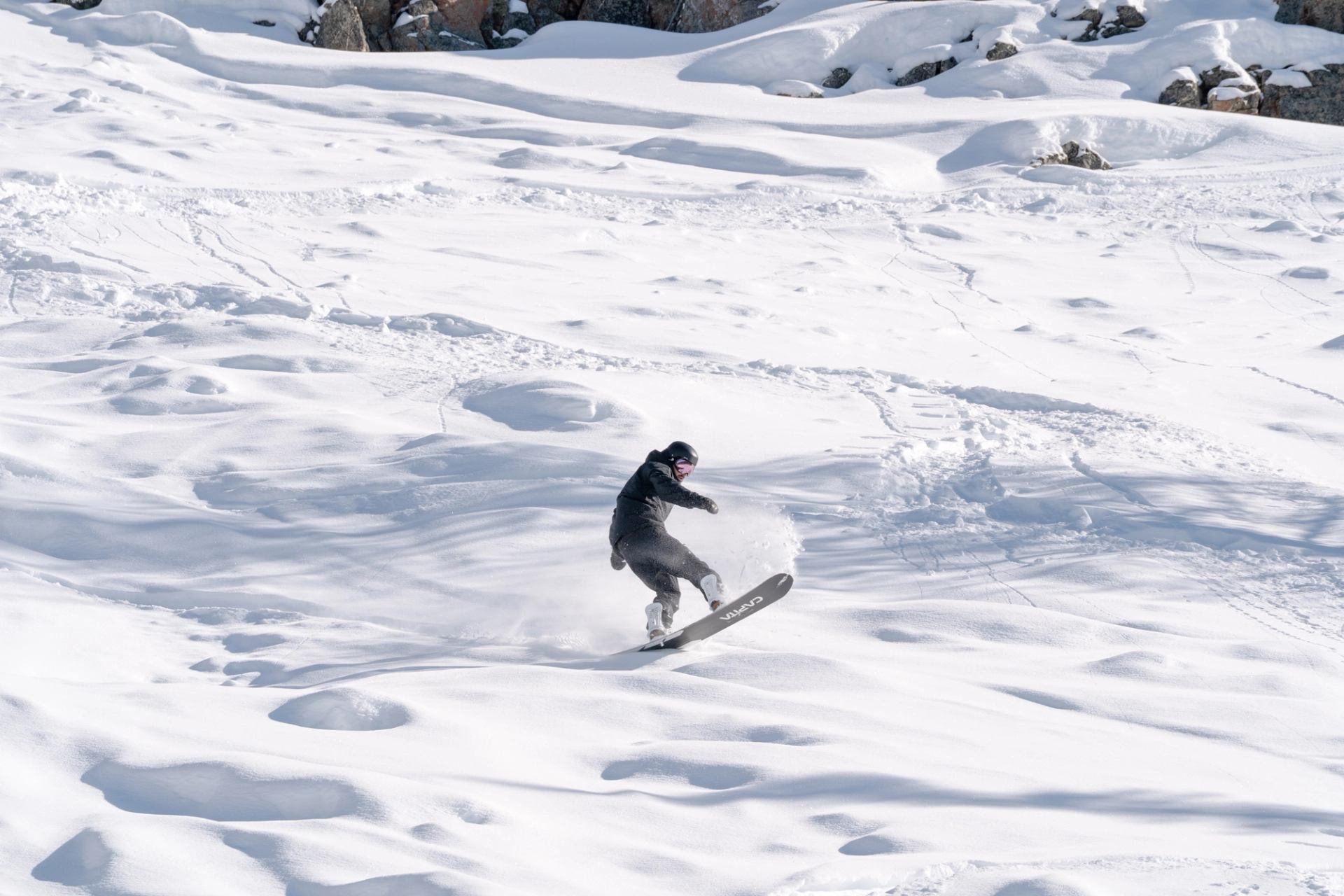 Snowboarder carving through fresh snow on an open winter slope.