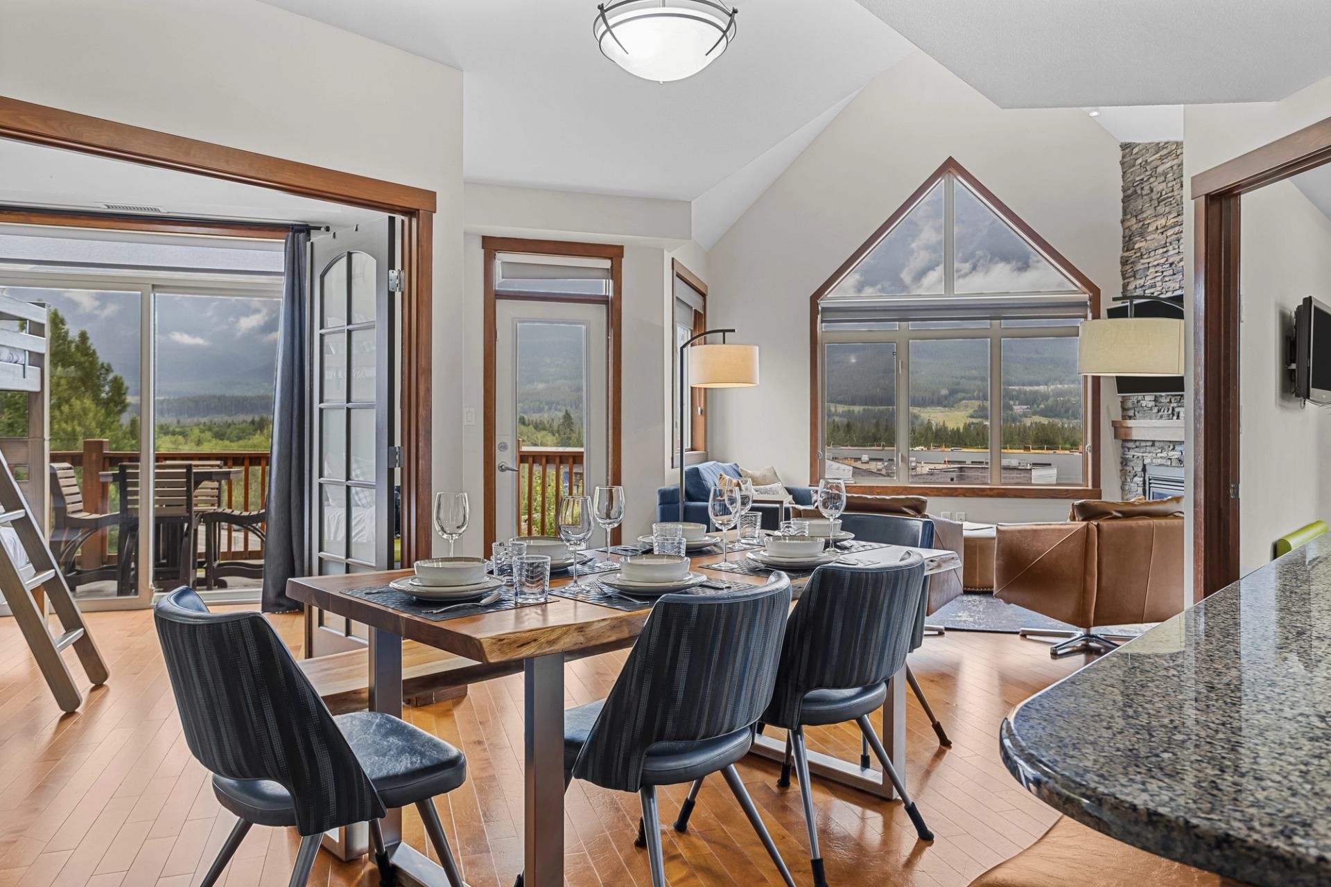 Dining area with a set table, mountain views, balcony and adjoining living room.