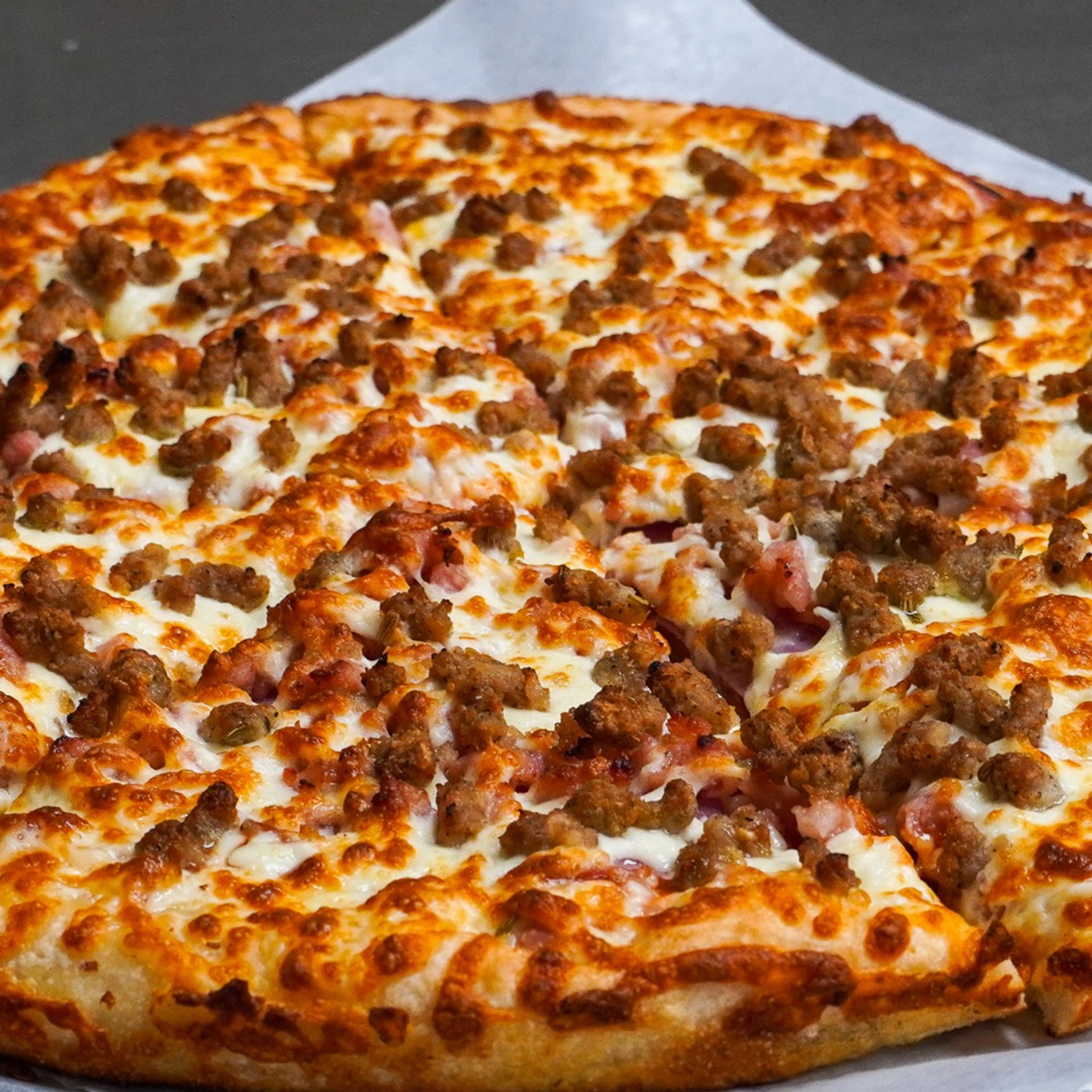 Pan-proofed pizza topped with savoury ham, pepperoni, bacon, sausage, and ground beef.