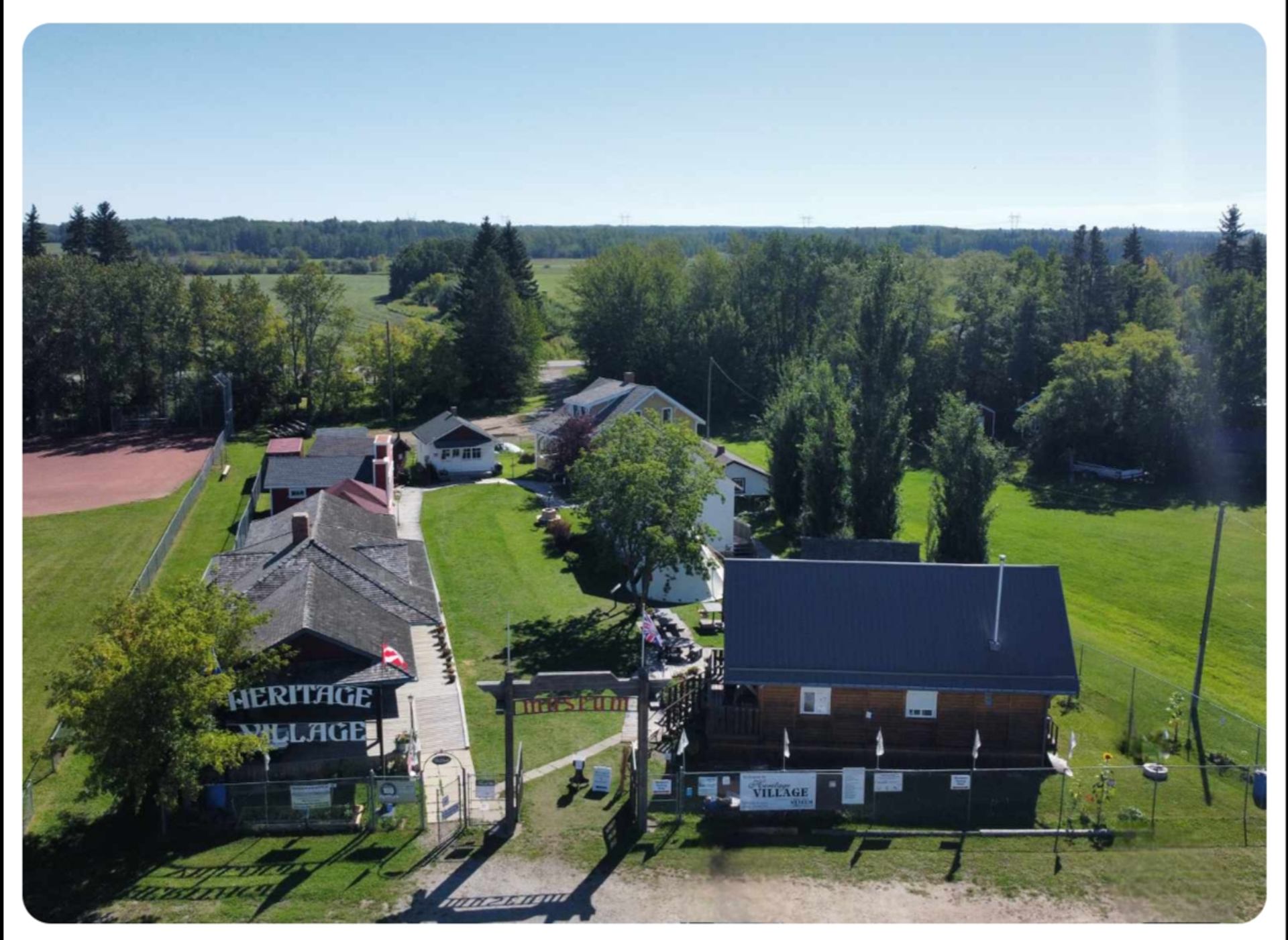 Aerial view of Heritage Village buildings, entrance gate and surrounding green fields.