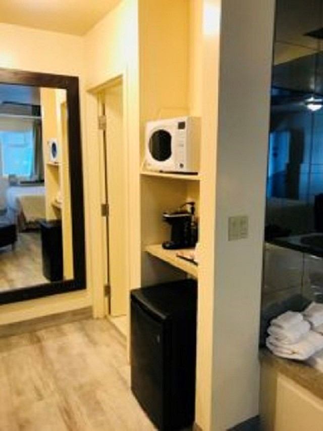 Hotel room amenities with microwave, coffee maker, mini fridge, and mirror.