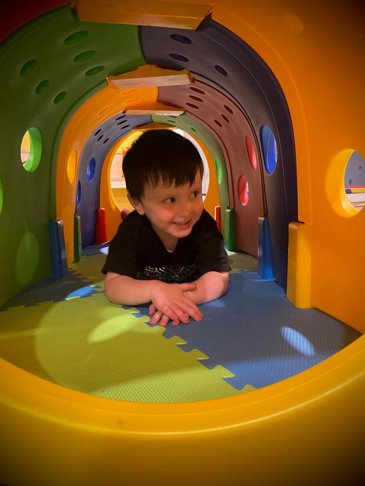 Child playing in a colorful indoor tunnel at Cubz Play Cafe.