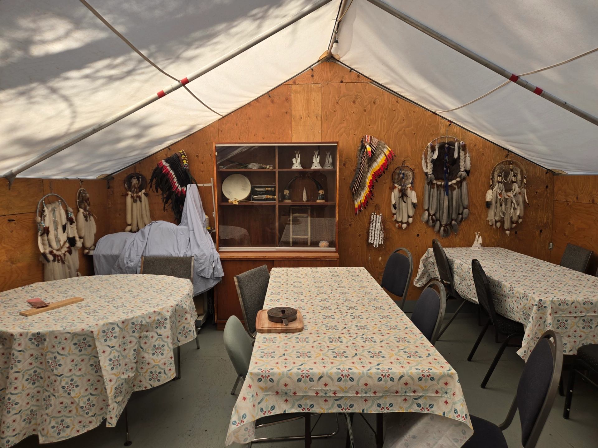 Inside the dinning wall tent table and chairs, wooden walls, indigenous head dresses, dream catcher
