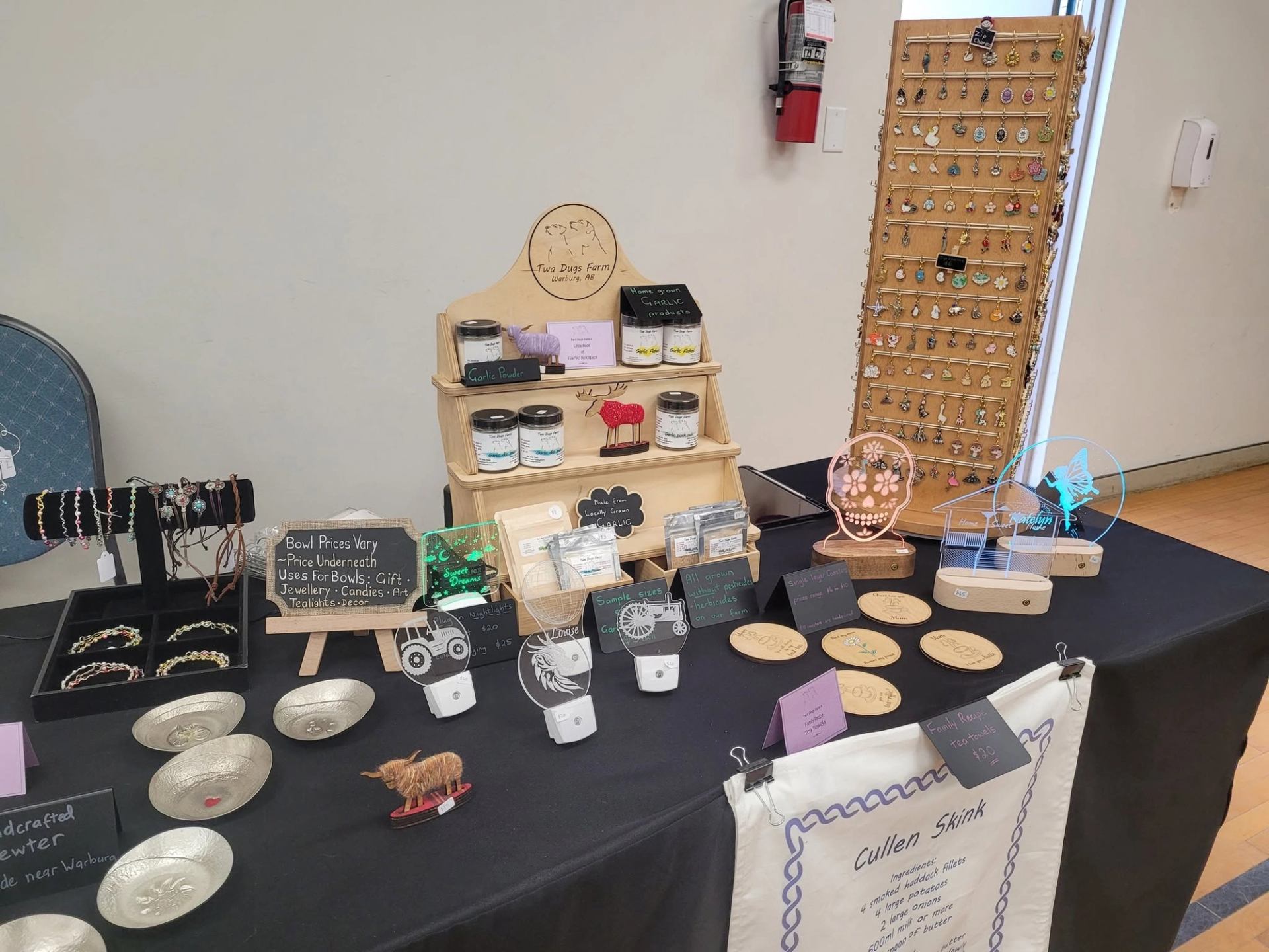 A display table features handmade crafts, jewelry, specialty products, signs, and decorative items.