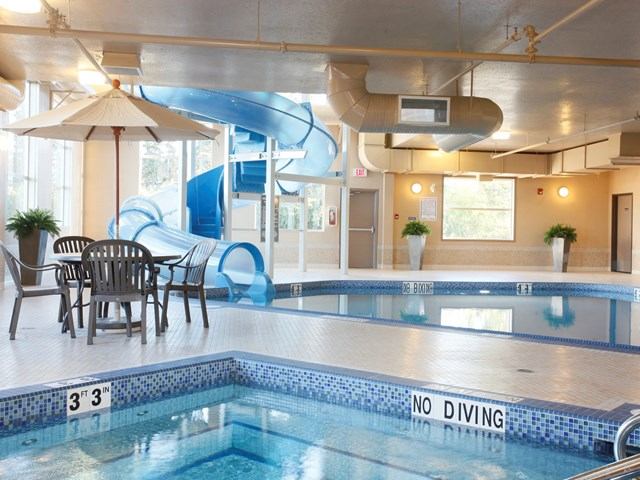 Indoor pool area featuring blue waterslide, tables, and chairs