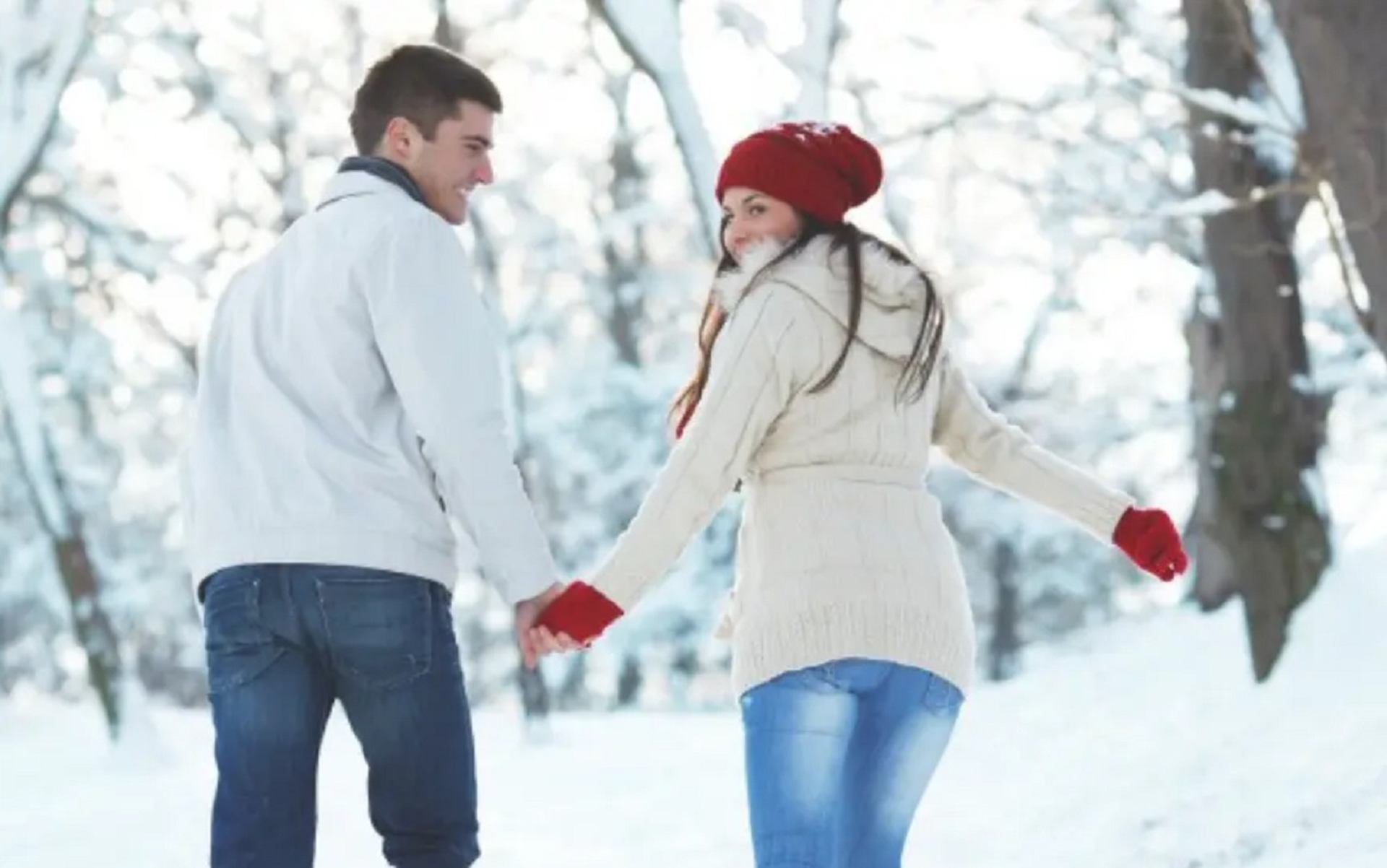 Couple walking hand in hand through a snowy forest at Rocky Mountain Couples Retreat.