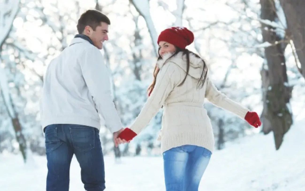 Couple walking hand in hand through a snowy forest at Rocky Mountain Couples Retreat.
