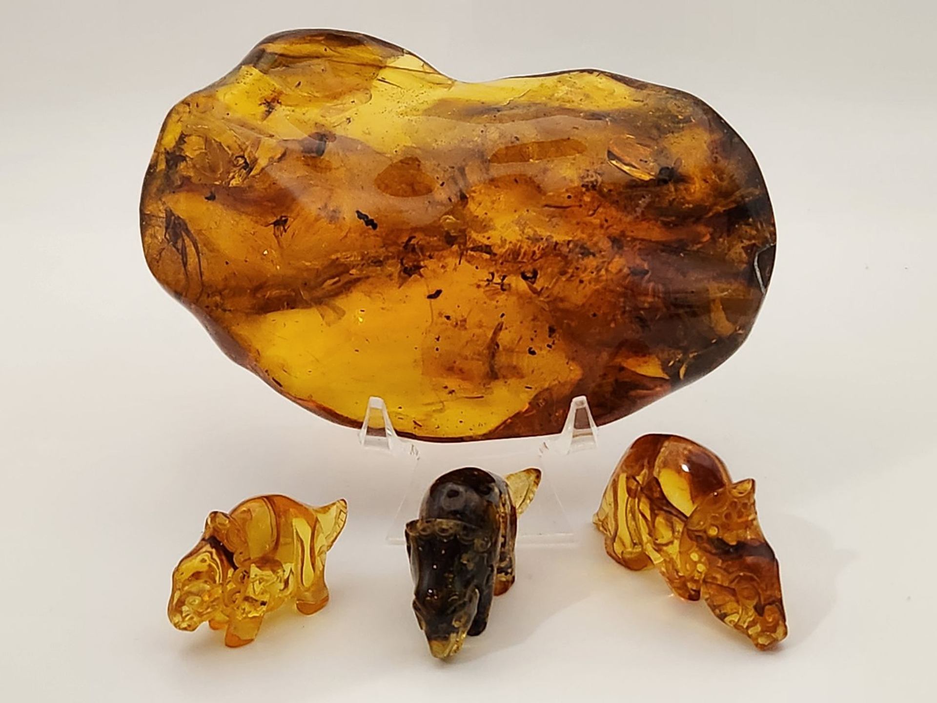 Large amber specimen displayed with small amber animal carvings on a white background.