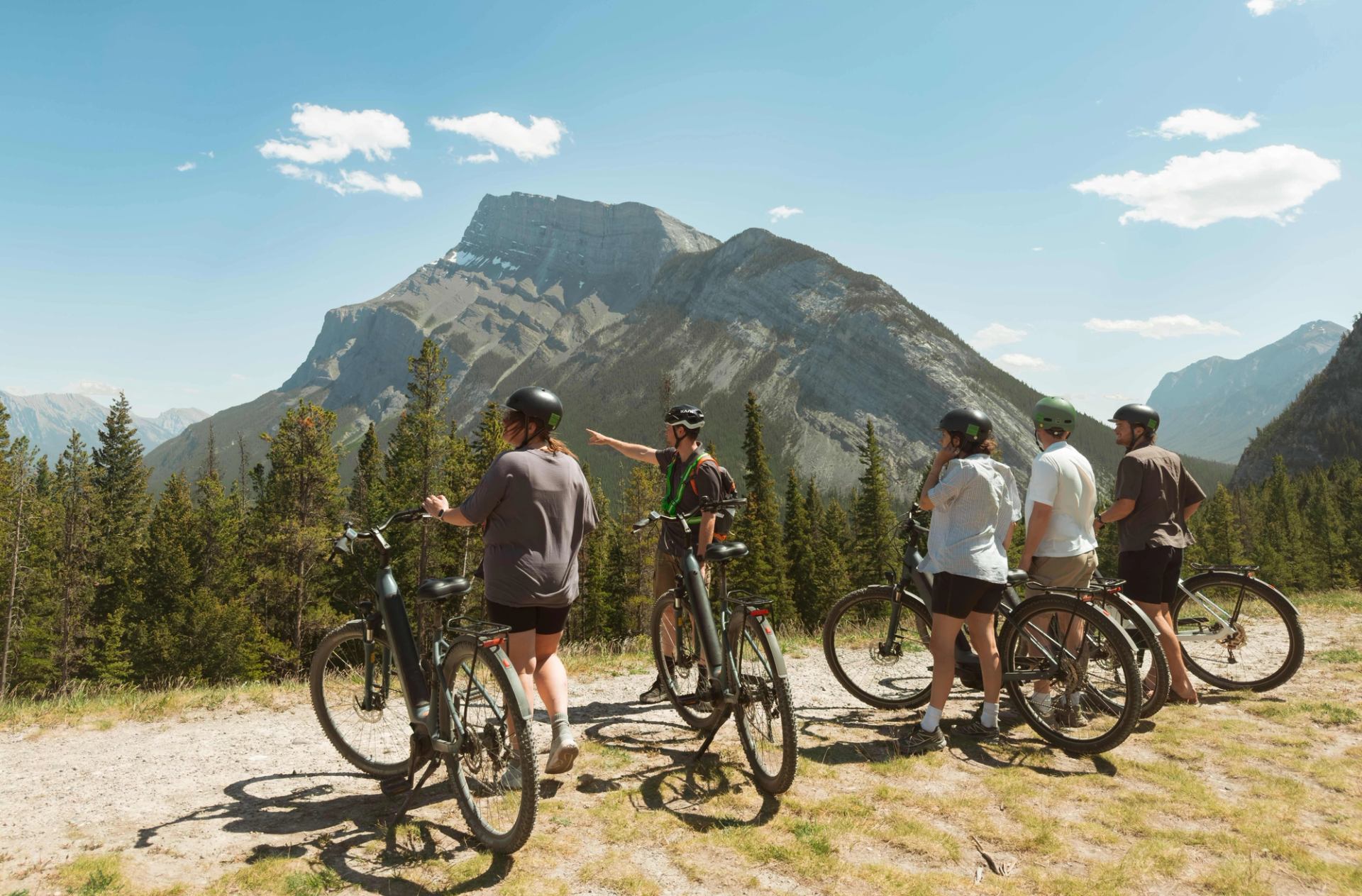 Cyclists stopped at a lookout with panoramic mountain scenery in Banff.