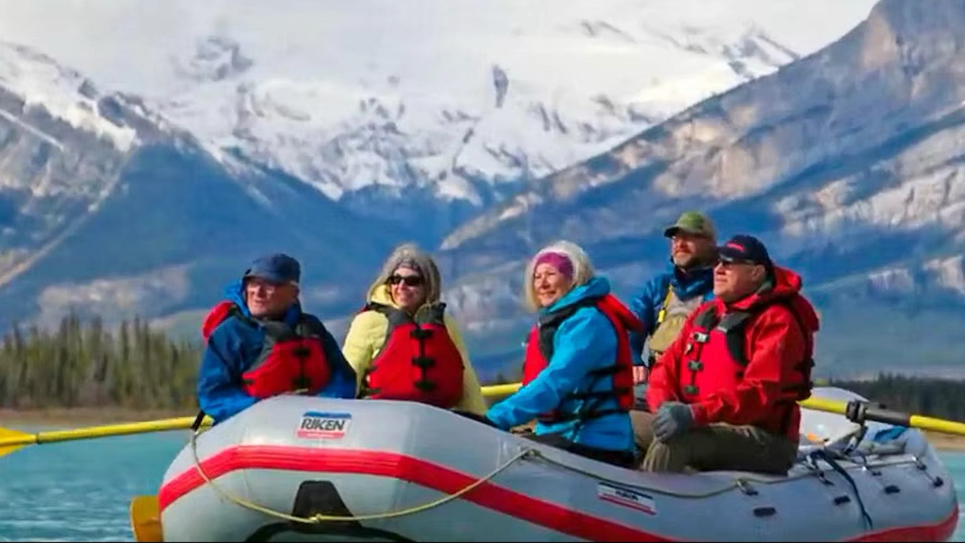 A group of people floating up the river in a raft.