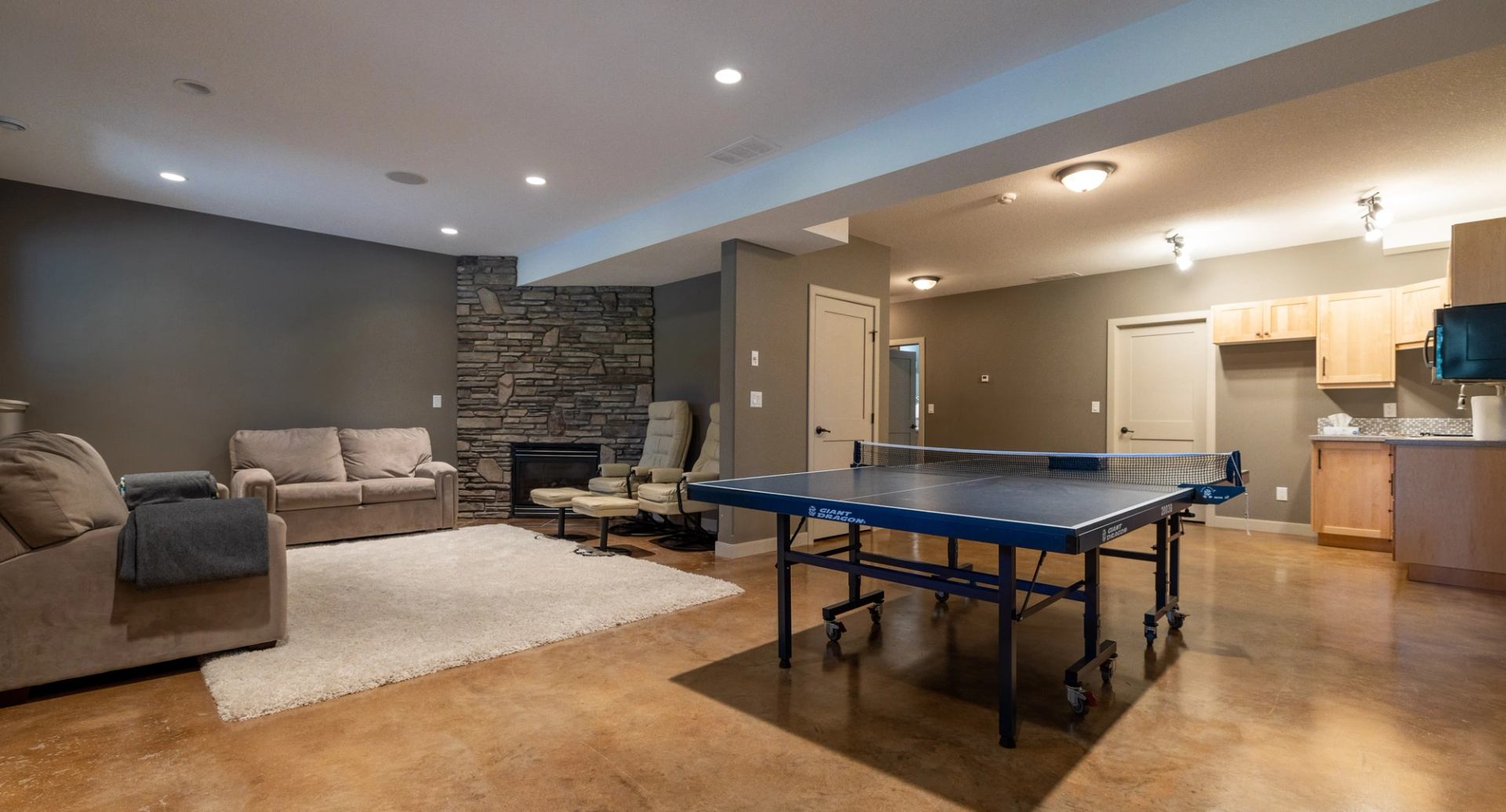 Basement with ping pong table, fireplace, and kitchenette.