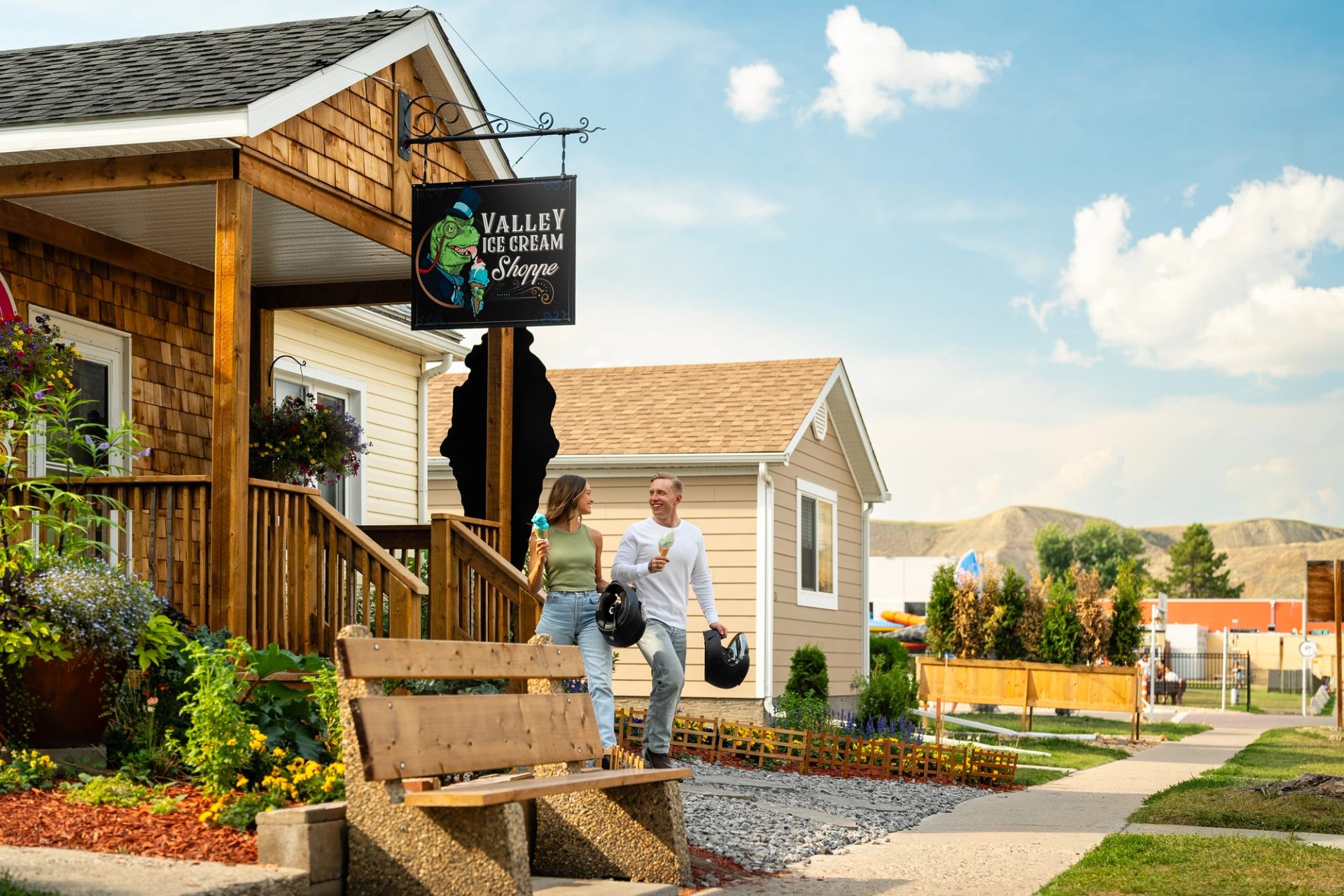 Two friends walk out from an ice cream shop in Drumheller with their ice cream and motorcycle helmet