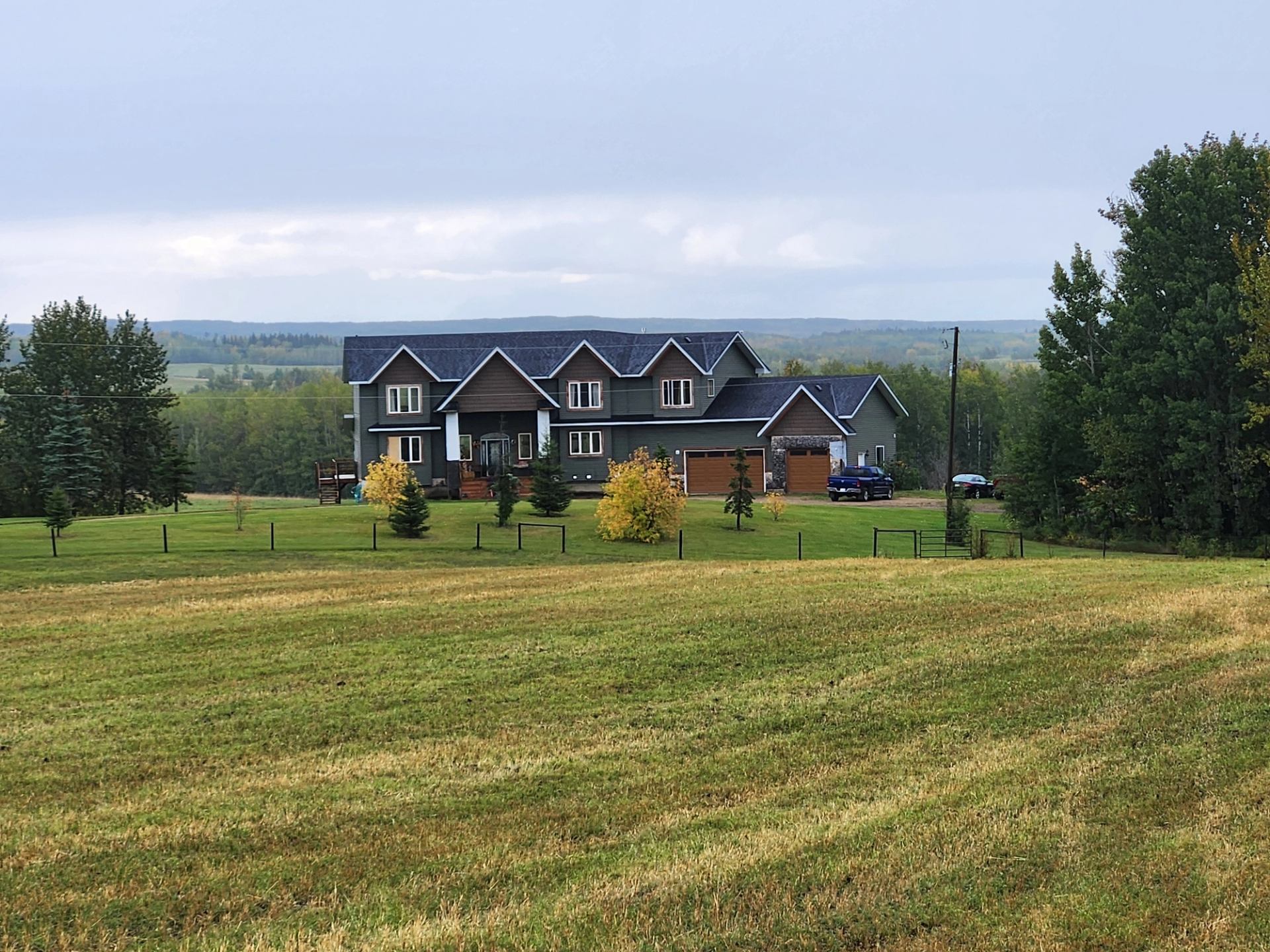 Ranch guest house with gabled roof, large windows, and garage on a green lawn.