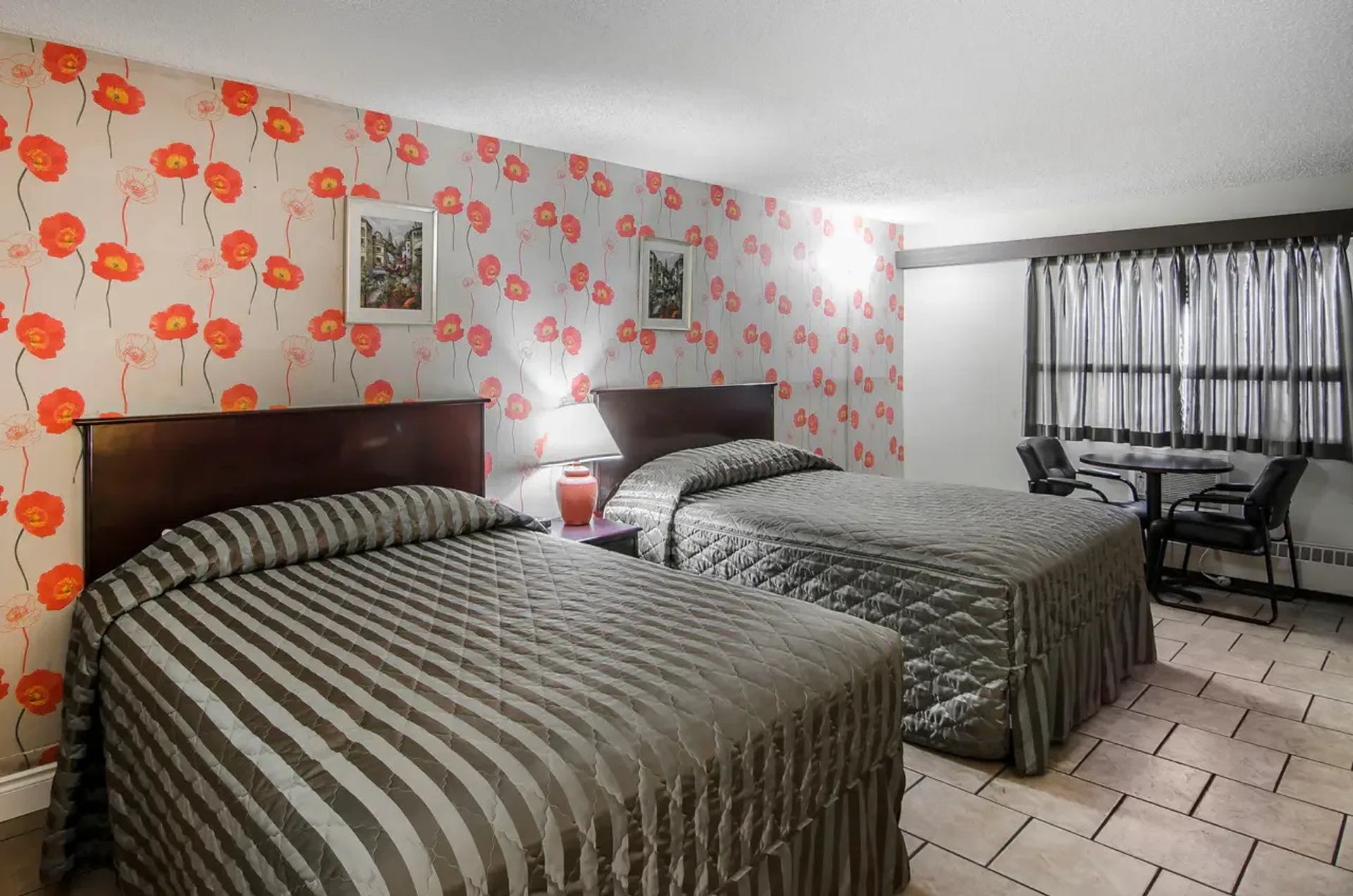 Hotel room with two queen beds, seating area, and warm lighting.