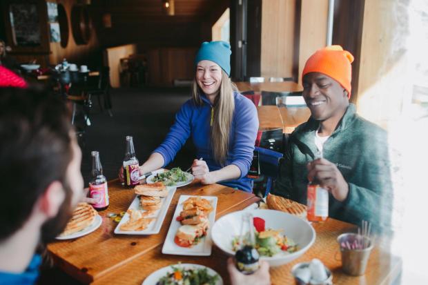 A group of skiers and snowboarders enjoying food and beer at the Cliffhouse Bistro in Mt. Norquay in Banff National Park