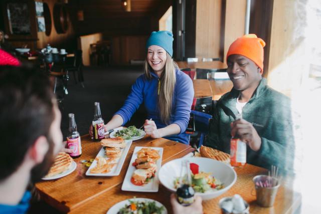 A group of skiers and snowboarders enjoying food and beer at the Cliffhouse Bistro in Mt. Norquay in Banff National Park