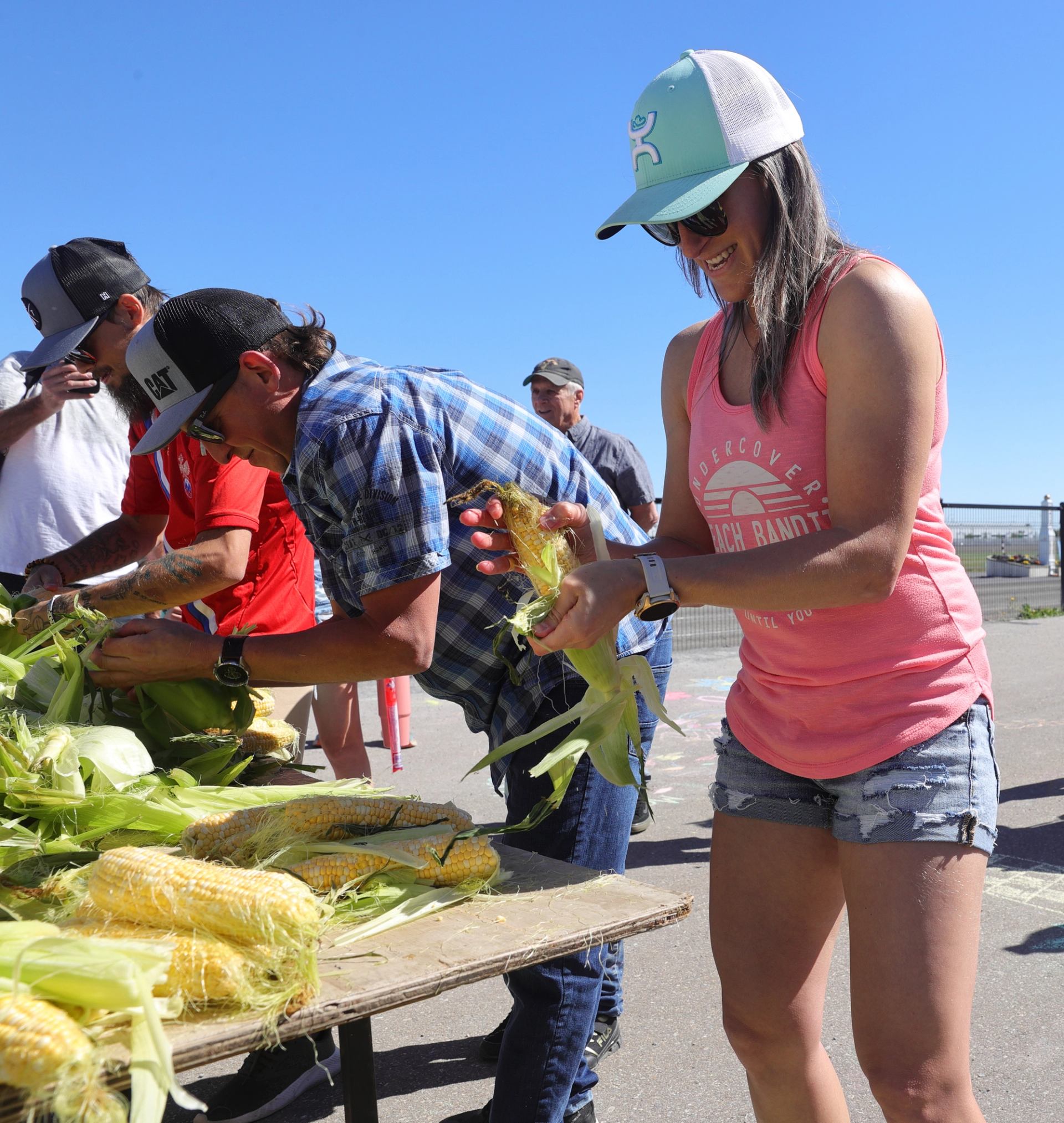 People peel corn at a table during Cornstock festivities