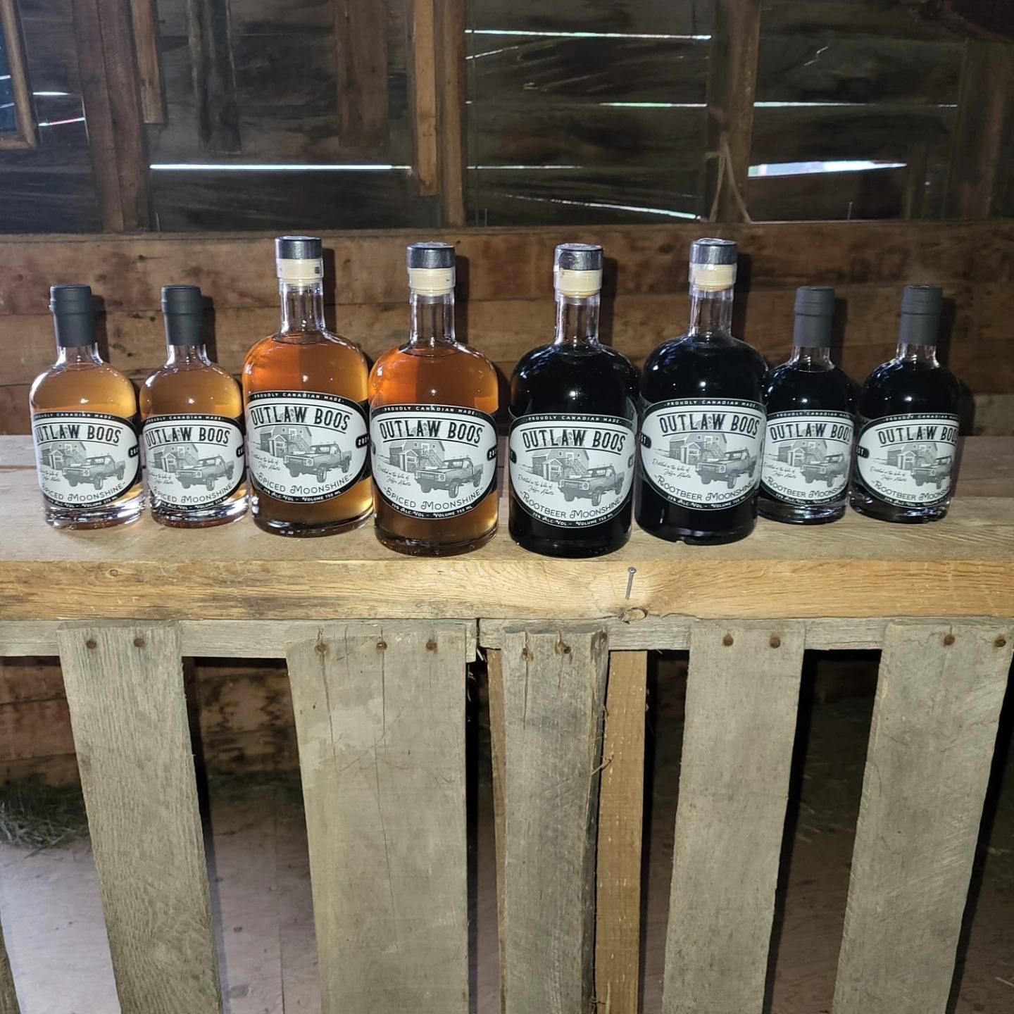 Row of Outlaw Boos moonshine bottles displayed on a rustic wooden shelf