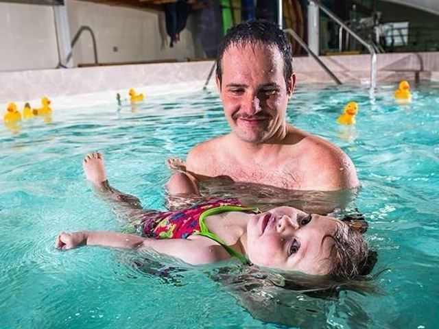 A father teaching his daughter to swim at the aquatic centre