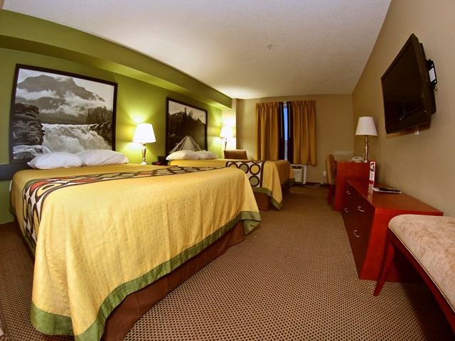 Hotel room with two beds, green accent wall, and framed art at Super 8 Sherwood Park.
