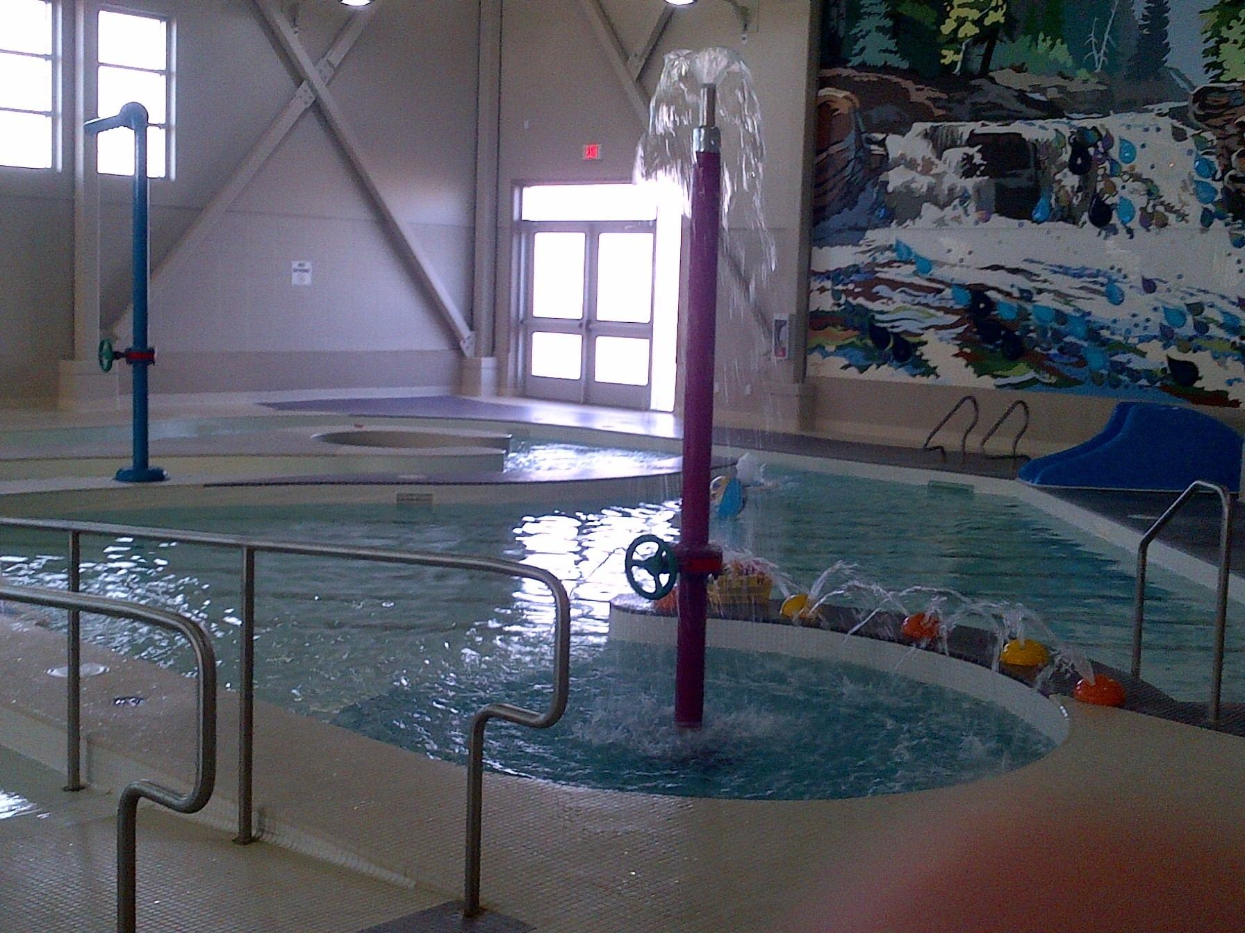 Indoor swimming pool, water falling fountain, and mural on the wall at recreation centre.