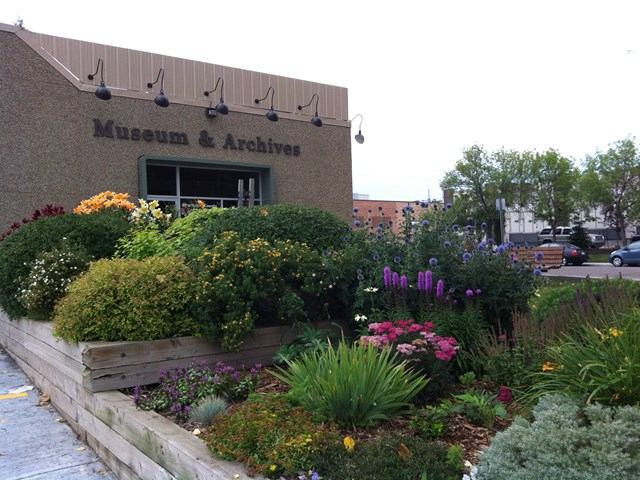 Museum & Archives building with colorful garden in front.