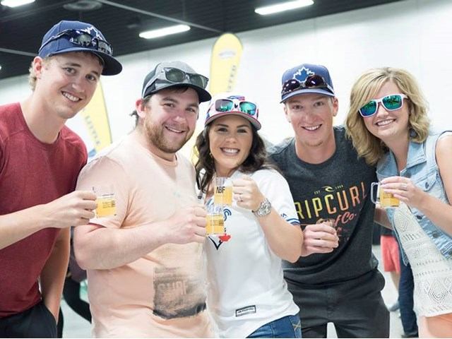 Group of friends holding beer samples at indoor craft beer festival.