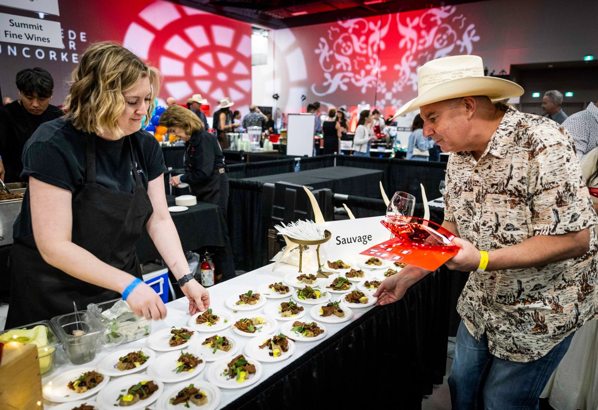  Tasting table lined with plated dishes as a guest selects a sample