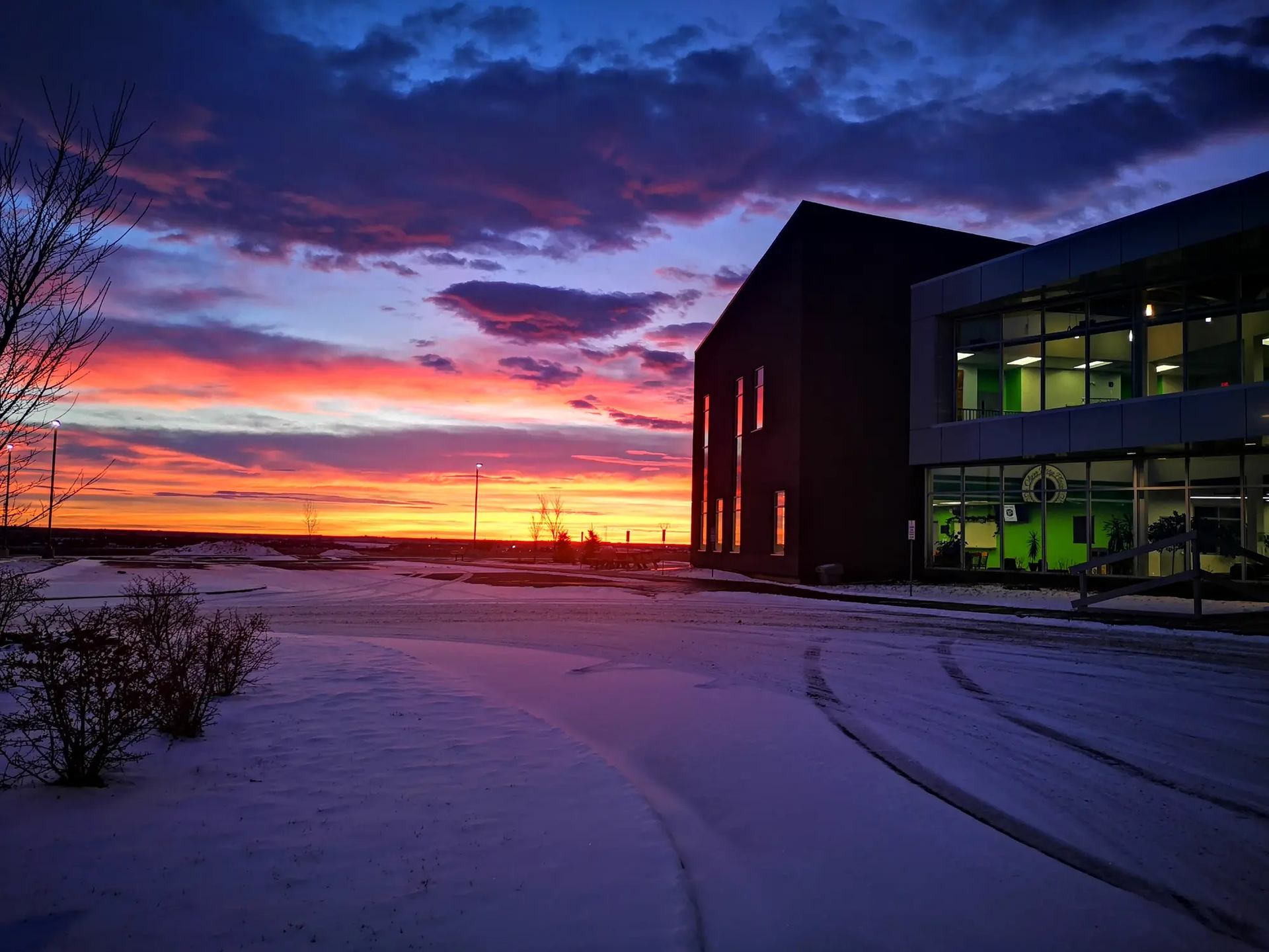 Snowy sunset at Regional Field House with vibrant sky and glowing windows.