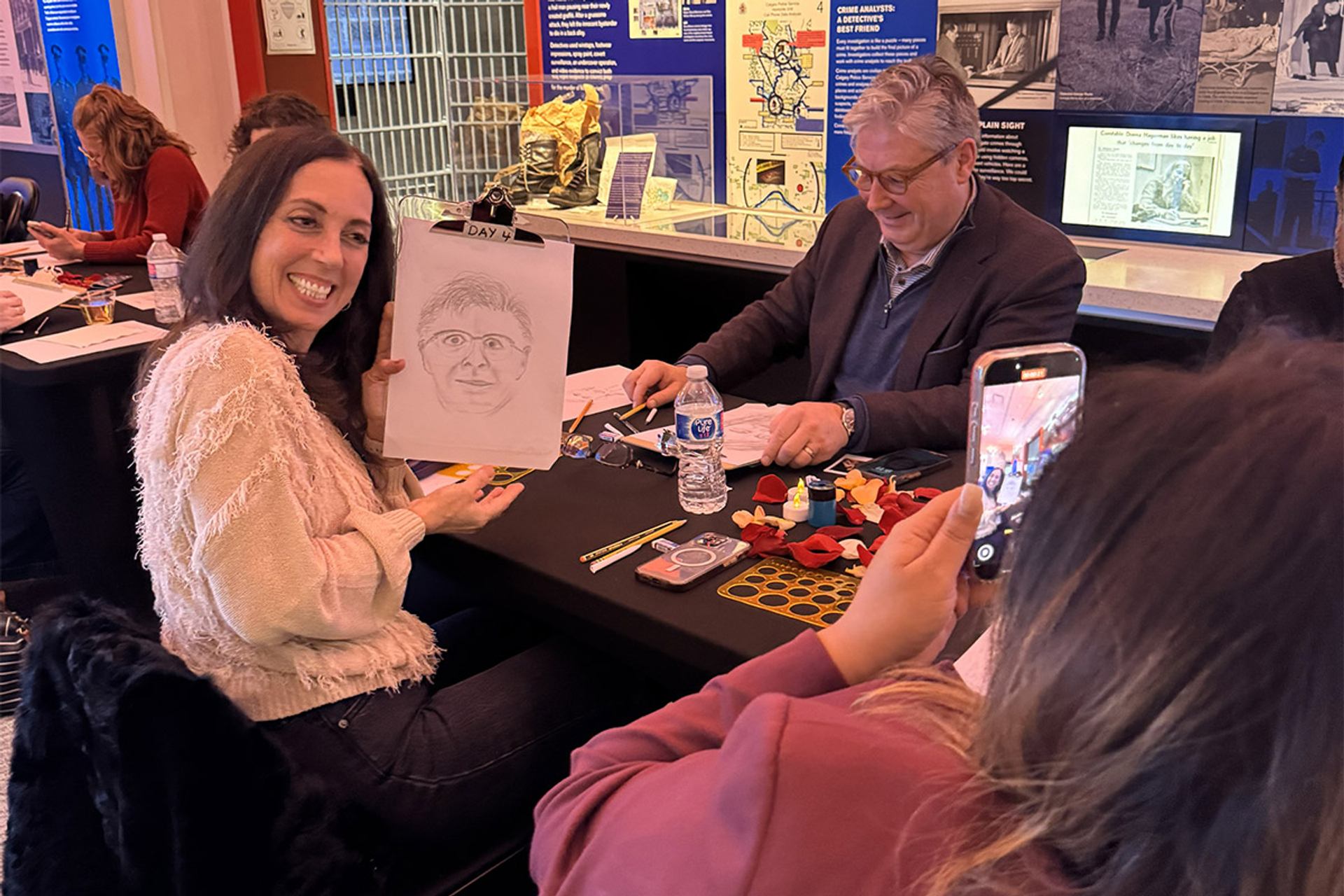Participants sketching and sharing artwork at a true crime-themed Sip & Sketch event.