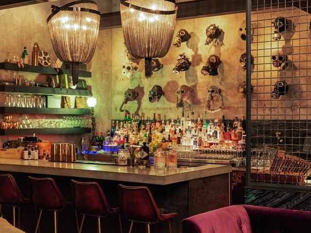 Bar with hanging lights, eclectic masks on concrete wall