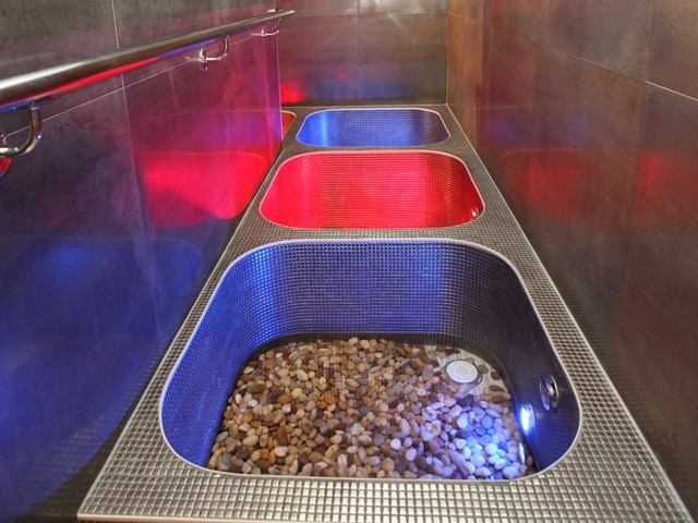 Three spa foot baths with pebbles and colored lighting.
