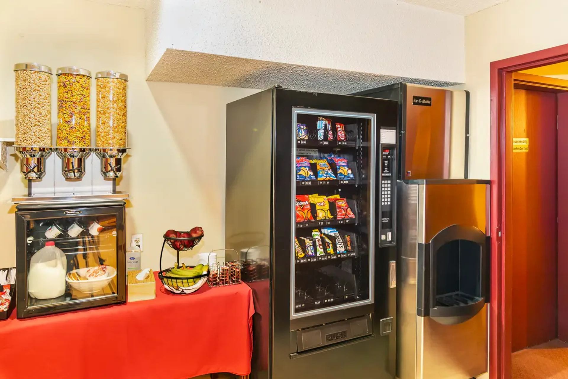 Snack area with cereal dispensers, fruit, refrigerated milk, vending machine and ice maker.