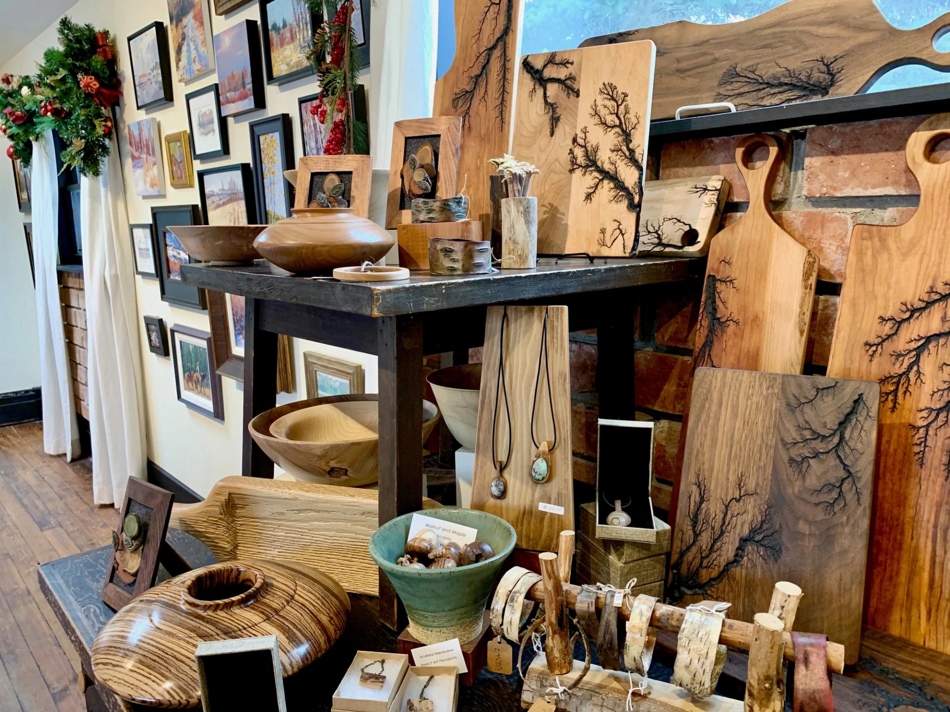 Handcrafted wooden bowls, boards, and art in a cozy gallery setting.