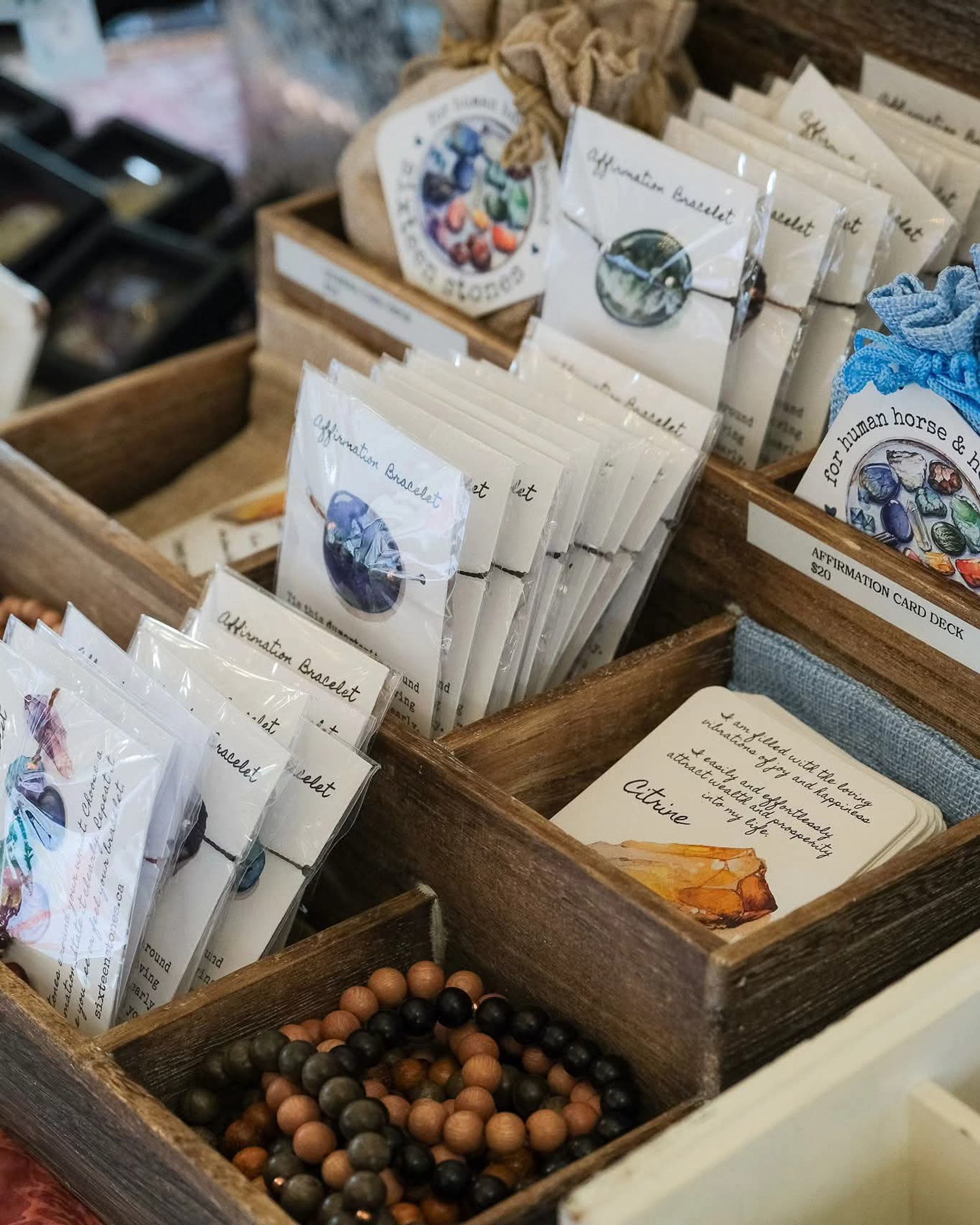 Wooden box with seed packets, small tied bags, and natural beaded bracelets.