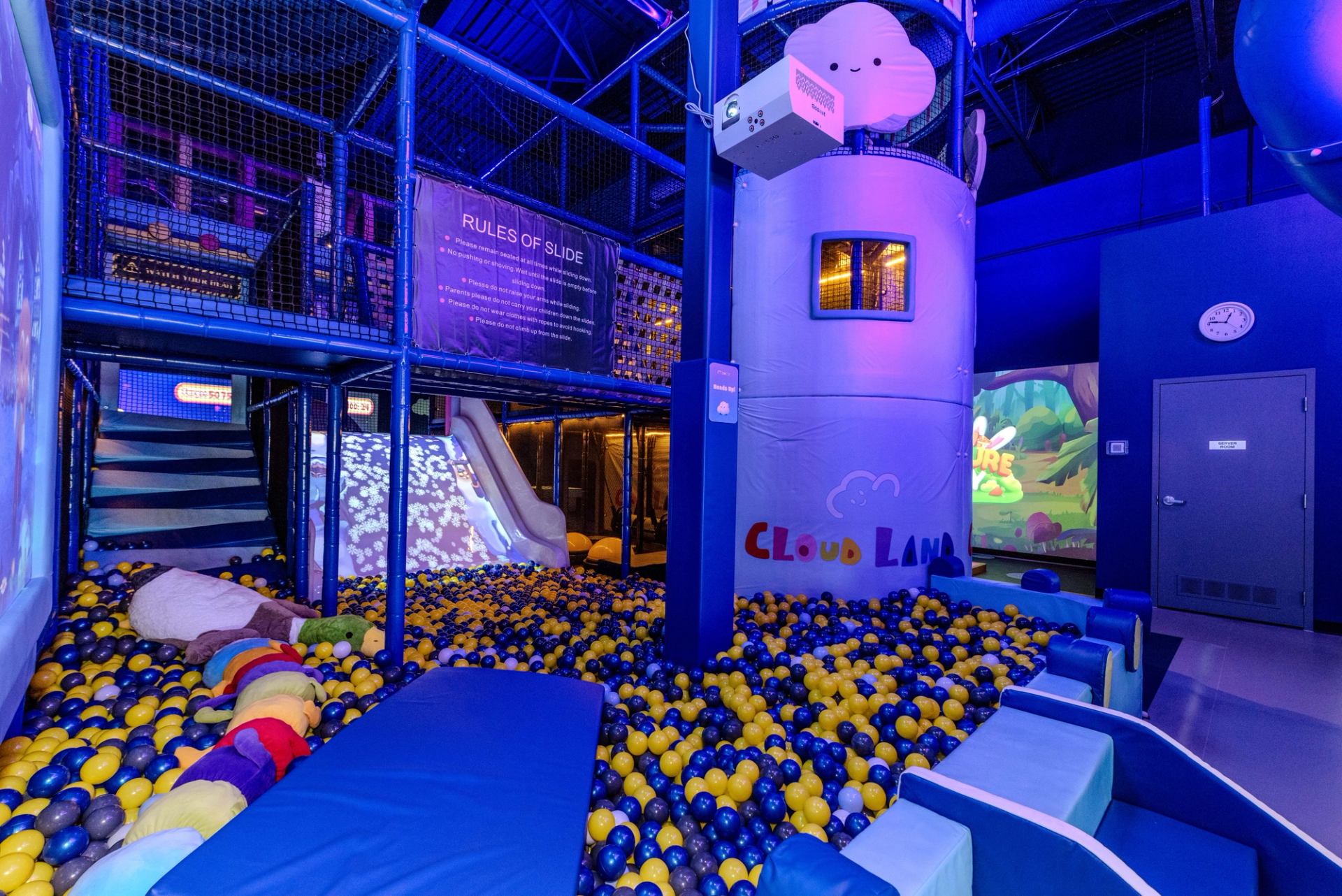 Indoor play zone with ball pit, slides, and Cloud Land-themed tower in vibrant blue lighting.