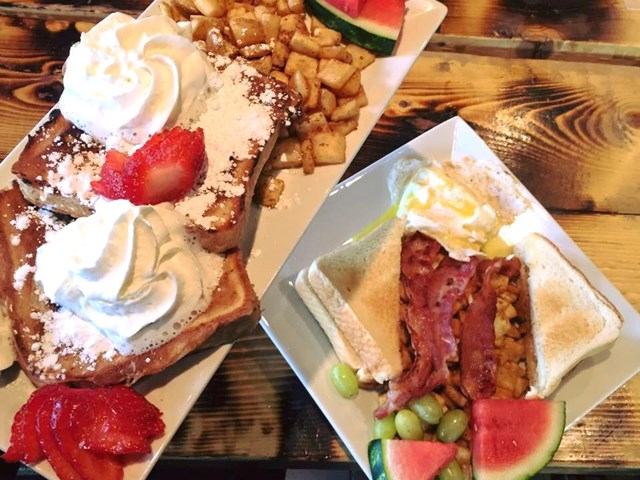 Hearty breakfast plates with toast, eggs, bacon, fruit, and French toast.